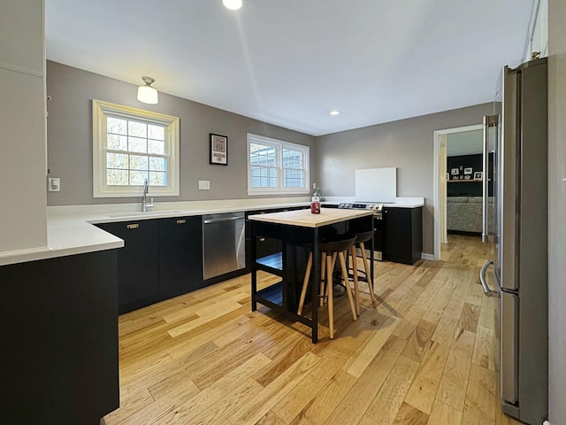 kitchen featuring sink, stainless steel appliances, kitchen peninsula, and light wood-type flooring