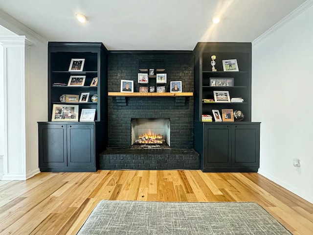 unfurnished living room with hardwood / wood-style flooring, built in shelves, ornamental molding, and a fireplace