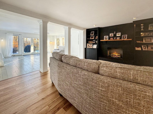 living room featuring a fireplace, hardwood / wood-style flooring, ornate columns, and built in features