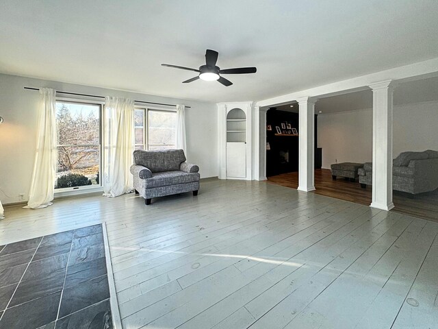 unfurnished room featuring decorative columns, ceiling fan, and wood-type flooring