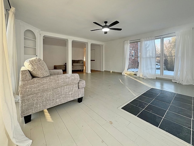 interior space with ceiling fan, wood-type flooring, and decorative columns