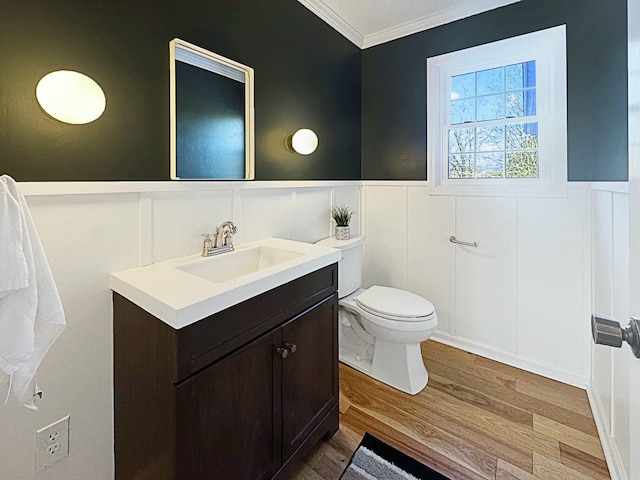 bathroom with hardwood / wood-style floors, crown molding, vanity, and toilet