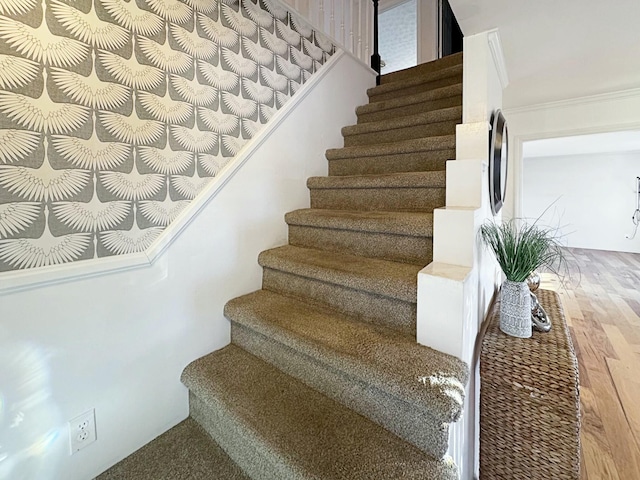 staircase with ornamental molding and hardwood / wood-style floors