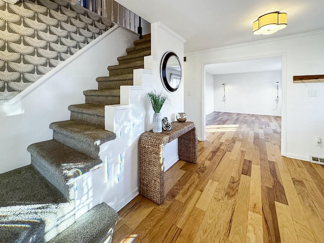 stairway featuring wood-type flooring and crown molding