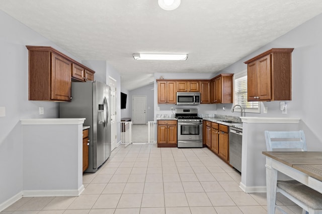 kitchen featuring lofted ceiling, appliances with stainless steel finishes, sink, and light tile patterned floors