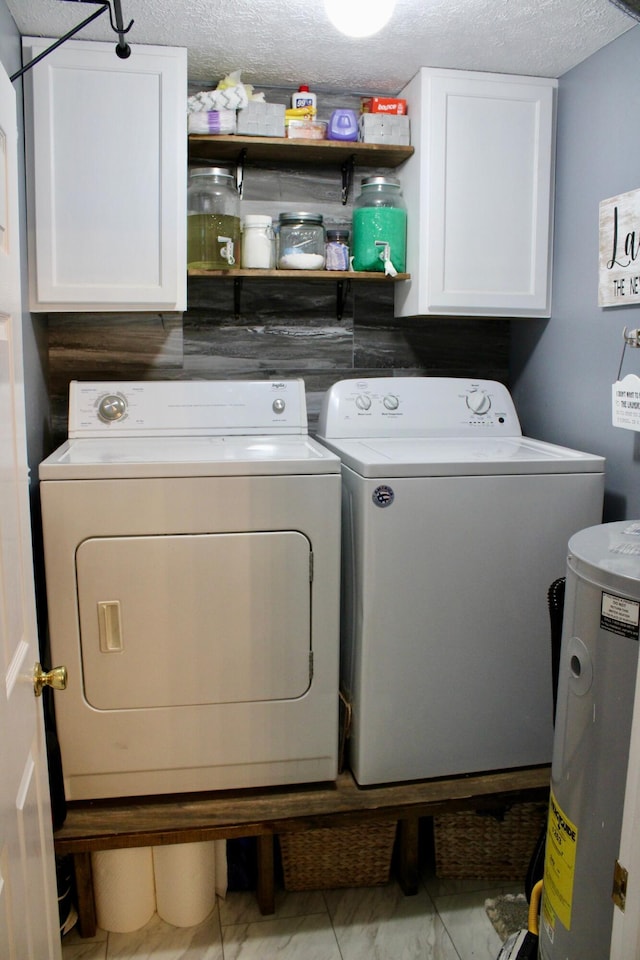 laundry area featuring washing machine and dryer, cabinets, and a textured ceiling