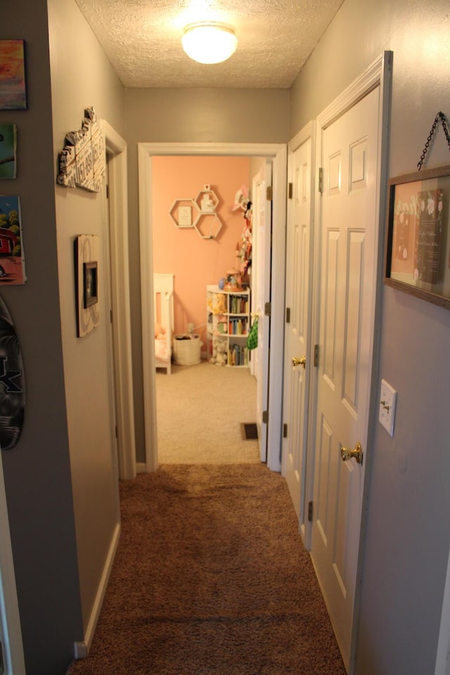 corridor with carpet floors and a textured ceiling