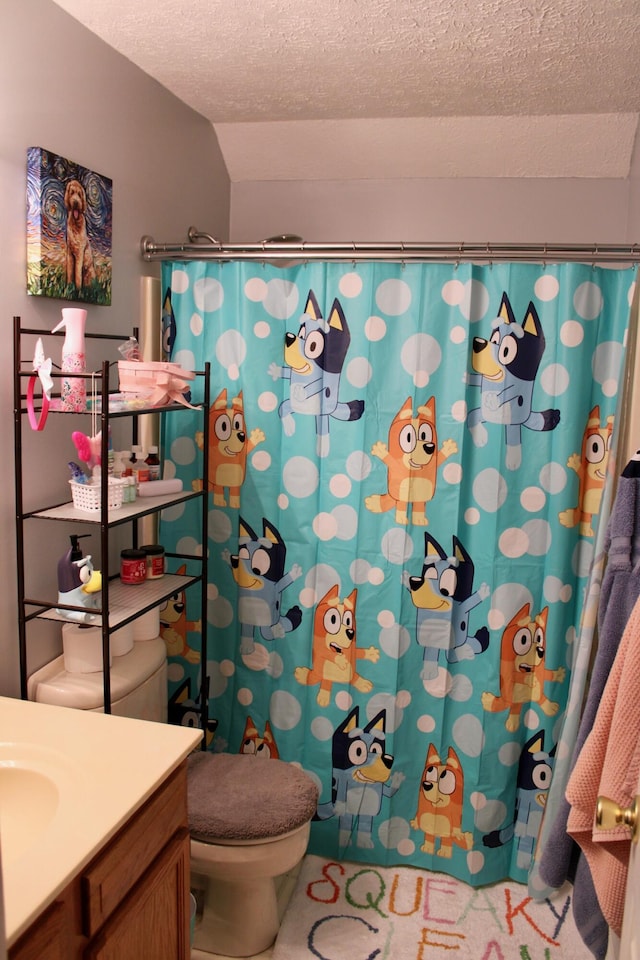 bathroom with vanity, a textured ceiling, curtained shower, and toilet