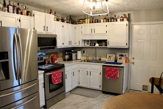 kitchen featuring stainless steel appliances, sink, a textured ceiling, and white cabinets