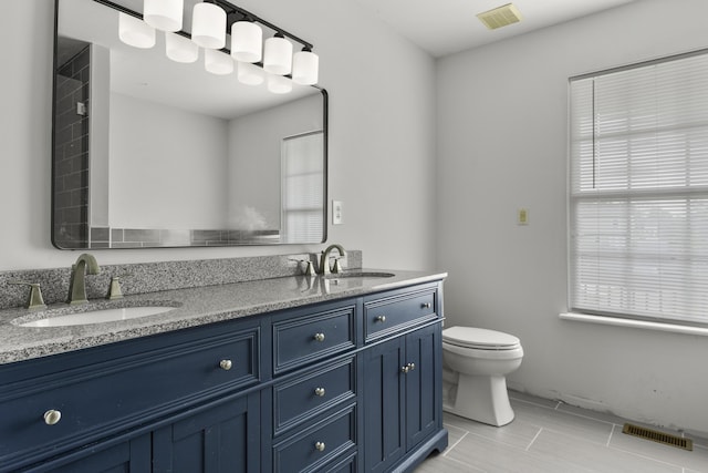 bathroom featuring visible vents, a sink, double vanity, and toilet
