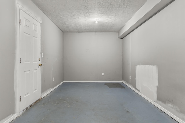 spare room featuring baseboards, a textured ceiling, and unfinished concrete flooring
