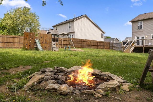 view of yard featuring a fenced backyard, a playground, a fire pit, and a deck