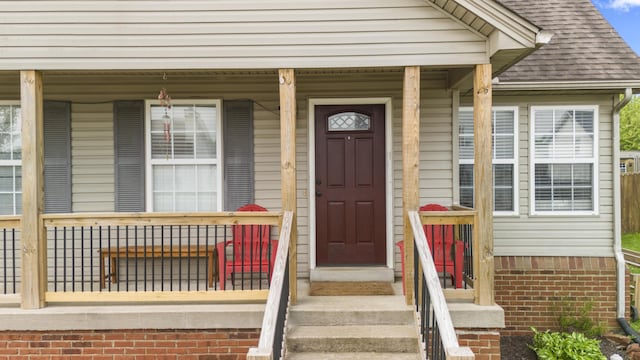 view of exterior entry with roof with shingles