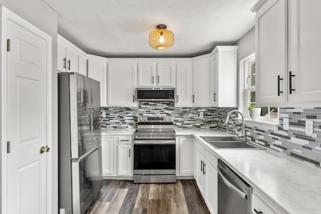 kitchen with decorative backsplash, light countertops, white cabinets, a sink, and appliances with stainless steel finishes