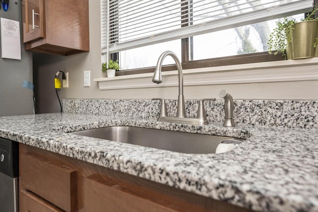 details with sink, light stone countertops, and dishwasher