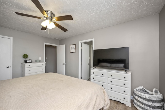 bedroom with ceiling fan, a textured ceiling, and light wood-type flooring