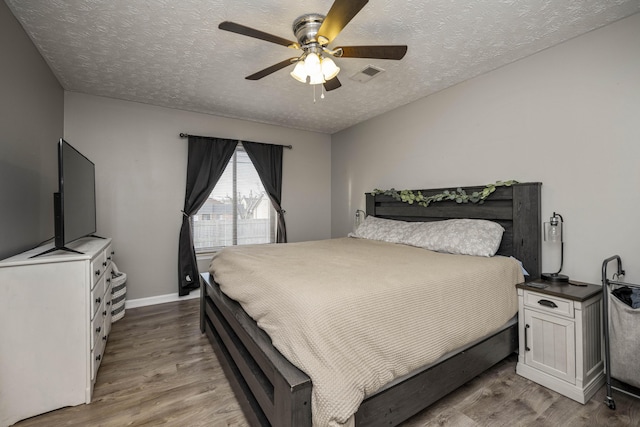 bedroom with ceiling fan, a textured ceiling, and light wood-type flooring