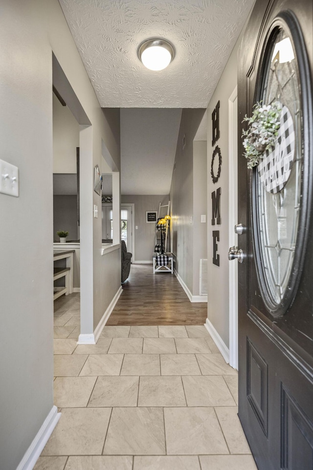 entryway featuring light tile patterned floors and a textured ceiling