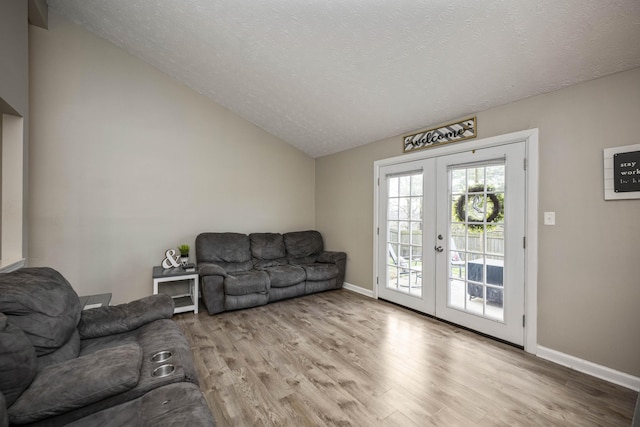 living room featuring french doors, lofted ceiling, a textured ceiling, and light wood-type flooring