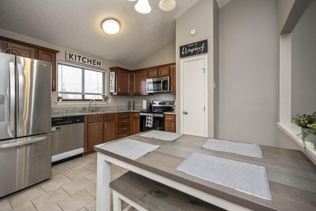 kitchen featuring sink, vaulted ceiling, a textured ceiling, and appliances with stainless steel finishes