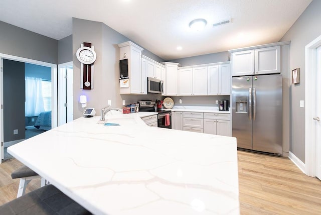 kitchen with white cabinetry, appliances with stainless steel finishes, kitchen peninsula, and sink