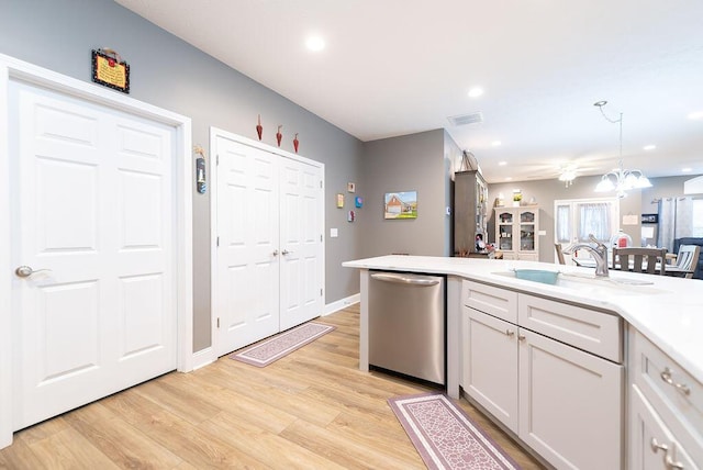 kitchen featuring sink, white cabinetry, decorative light fixtures, light hardwood / wood-style flooring, and stainless steel dishwasher