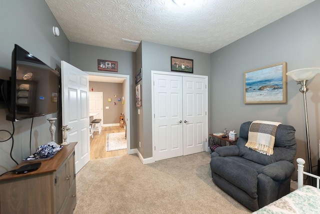 bedroom featuring light colored carpet, a closet, and a textured ceiling