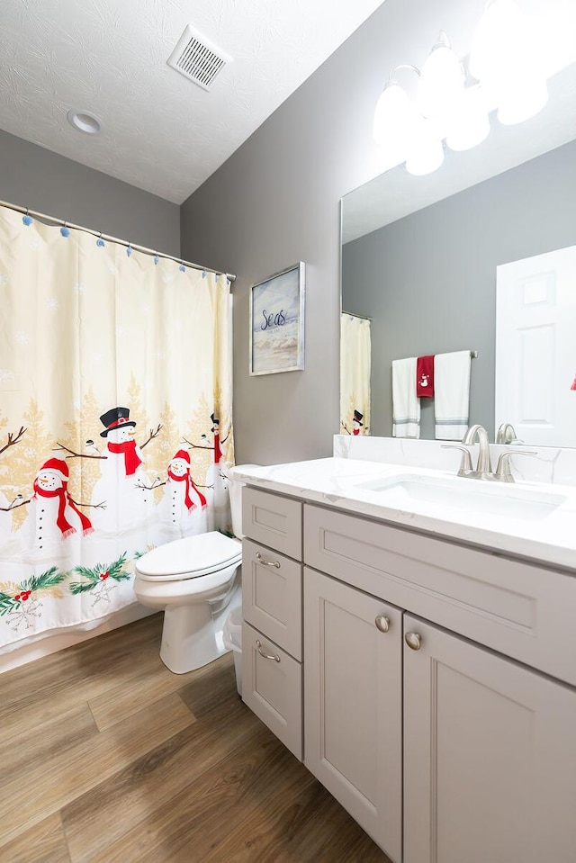 bathroom featuring vanity, hardwood / wood-style flooring, a textured ceiling, and toilet