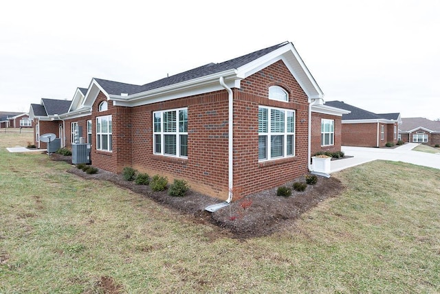 view of side of home with cooling unit and a lawn