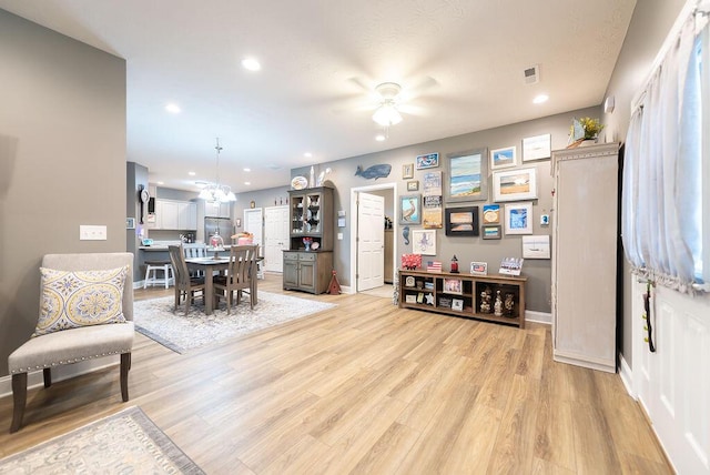 dining room featuring ceiling fan with notable chandelier and light hardwood / wood-style flooring