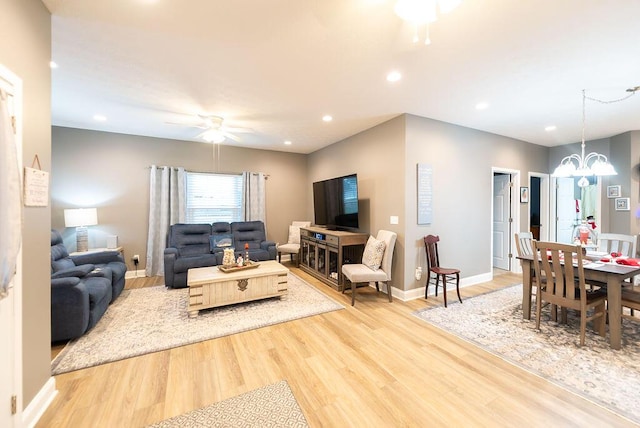 living room featuring light hardwood / wood-style floors and ceiling fan with notable chandelier