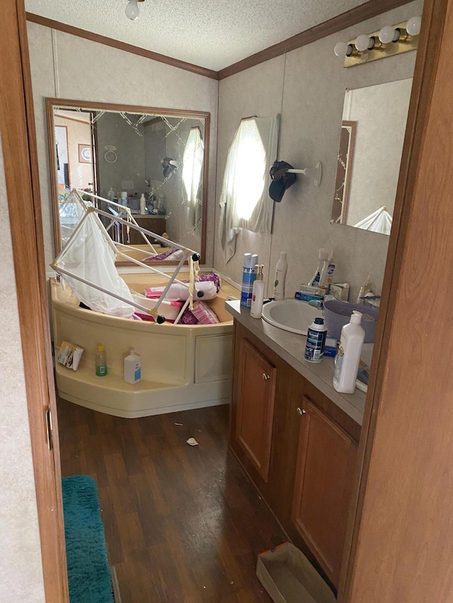 bathroom featuring crown molding, vanity, hardwood / wood-style flooring, and a textured ceiling