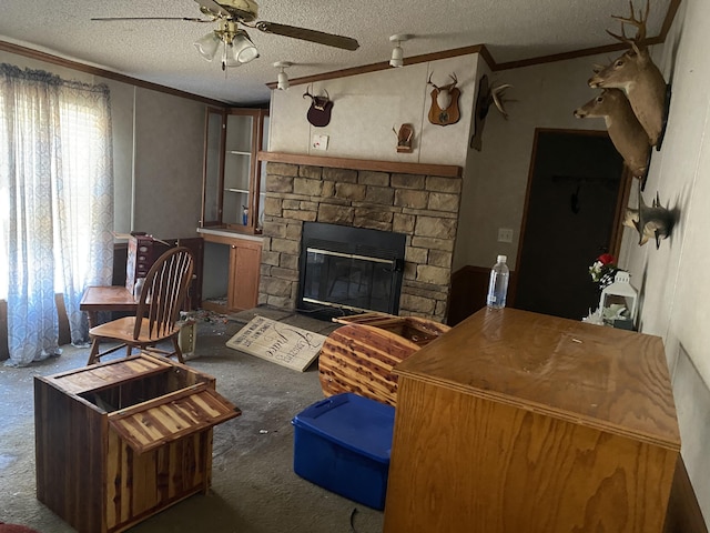 living room with ornamental molding, ceiling fan, a textured ceiling, and a fireplace