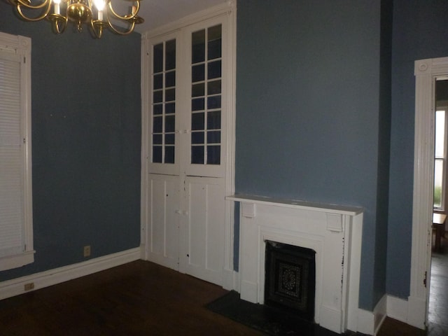 unfurnished living room featuring a notable chandelier and dark hardwood / wood-style flooring