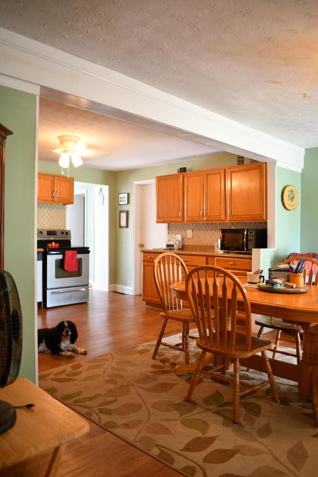 dining area featuring hardwood / wood-style floors, beamed ceiling, and a textured ceiling