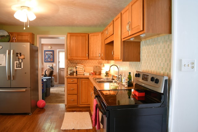 kitchen with appliances with stainless steel finishes, sink, decorative backsplash, light hardwood / wood-style floors, and a textured ceiling