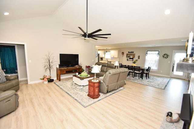 living room with light hardwood / wood-style flooring, ceiling fan, and vaulted ceiling