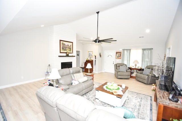 living room featuring ceiling fan, a large fireplace, lofted ceiling, and light hardwood / wood-style flooring