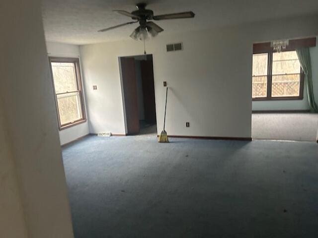 carpeted spare room featuring ceiling fan and a healthy amount of sunlight