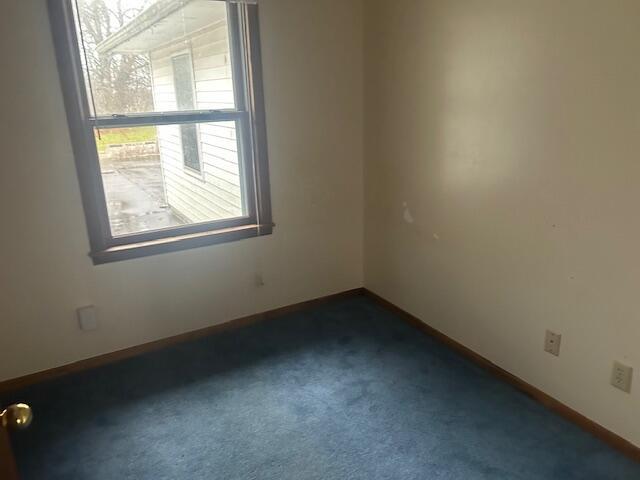 unfurnished room featuring dark colored carpet