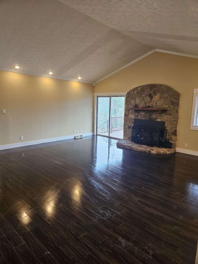 unfurnished living room with crown molding, a textured ceiling, dark hardwood / wood-style flooring, a stone fireplace, and vaulted ceiling