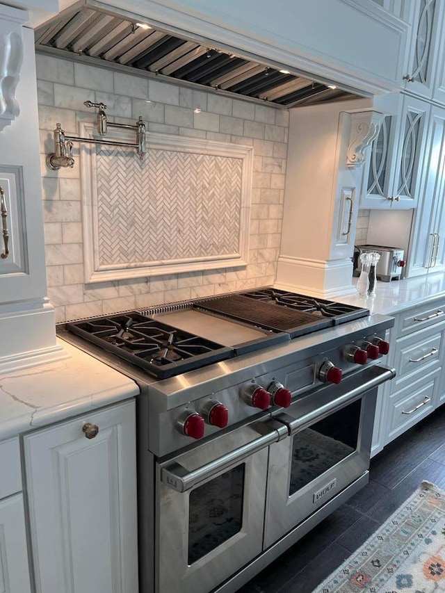 kitchen with white cabinetry, double oven range, tasteful backsplash, light stone countertops, and wall chimney exhaust hood