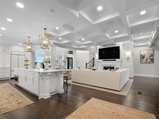 living room with decorative columns, dark hardwood / wood-style flooring, coffered ceiling, and beam ceiling