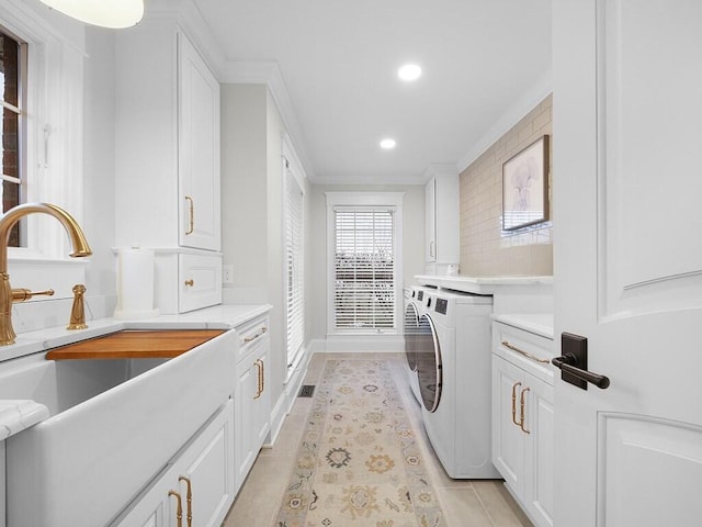 washroom with sink, cabinets, light tile patterned floors, ornamental molding, and independent washer and dryer