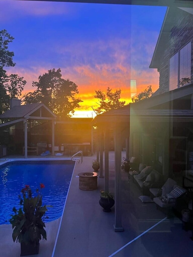 pool at dusk with a gazebo, an outdoor fire pit, and a patio