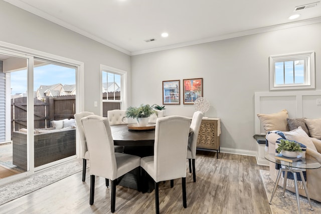 dining area featuring crown molding, a healthy amount of sunlight, and hardwood / wood-style flooring