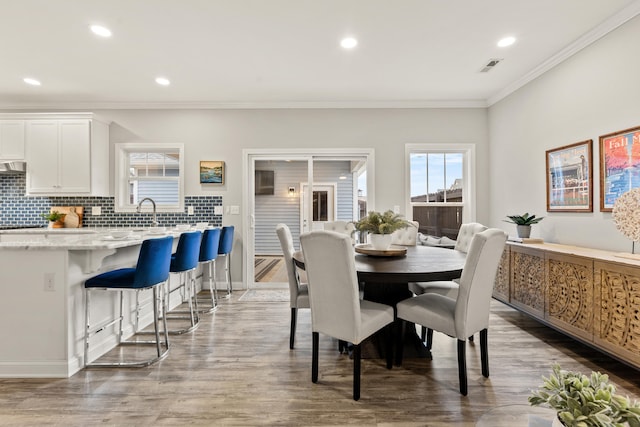 dining space featuring sink, crown molding, and wood-type flooring