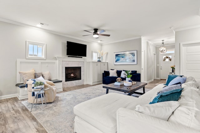 living room with crown molding, ceiling fan, a fireplace, and light hardwood / wood-style flooring