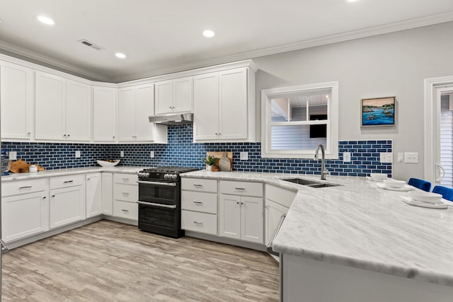 kitchen with sink, white cabinetry, light hardwood / wood-style flooring, ornamental molding, and range with two ovens