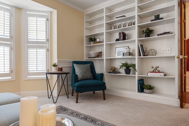 sitting room featuring built in shelves, ornamental molding, and carpet